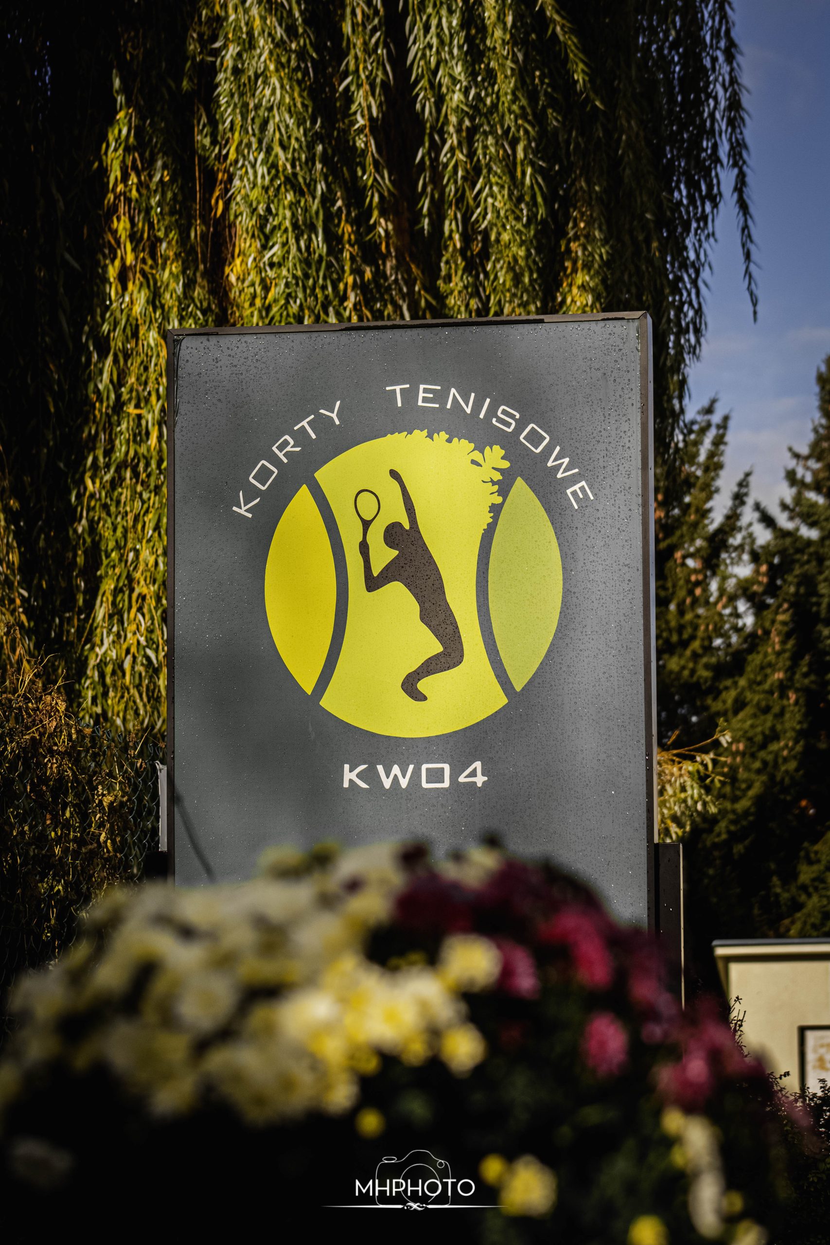 Tablica informacyjna z napisem Korty tenisowe KW04 i logo.